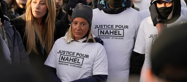 Mounia, die Mutter des verstorbenen Nahel (2.v.l) trägt ein T-Shirt mit der Aufschrift «Gerechtigkeit für Nahel», während einer Demonstration anlässlich der Freilassung des Polizisten aus der Untersuchungshaft, der den 17-Jährigen getötet hat.  (Foto: dpa Bildfunk, picture alliance/dpa/AP | Lewis Joly)