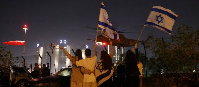 Israelis erwarten mit schwenkenden Fahnen die Ankunft der Geiseln in einem Helikopter. (Foto: Reuters, REUTERS/Ronen Zvulun)