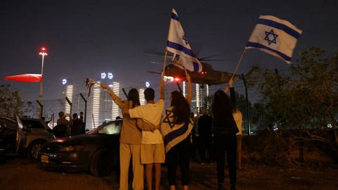 Israelis erwarten mit schwenkenden Fahnen die Ankunft der Geiseln in einem Helikopter. (Foto: Reuters, REUTERS/Ronen Zvulun)