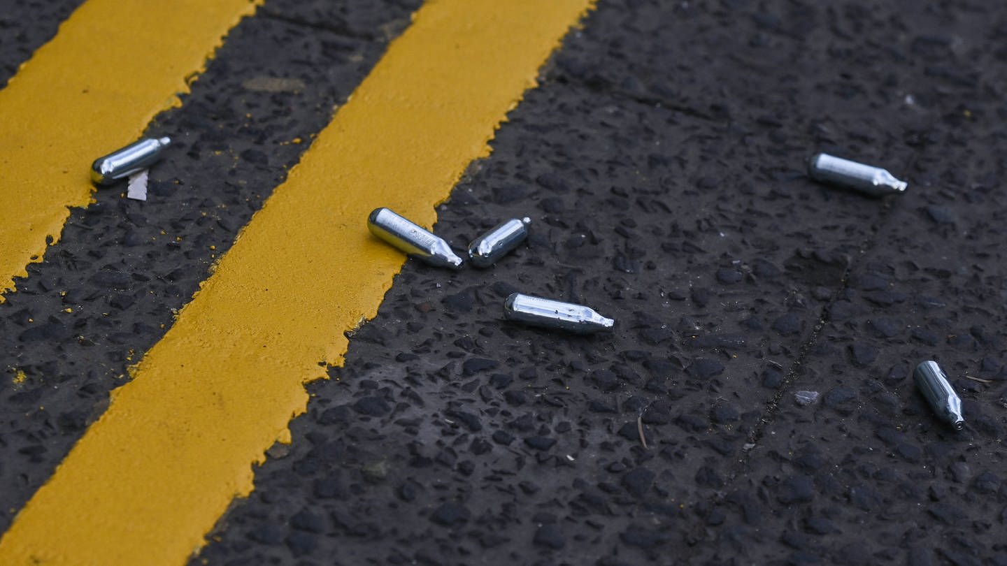 Lachgas-Kartuschen liegen auf der Straße. (Symbolbild) (Foto: IMAGO, IMAGO / NurPhoto)