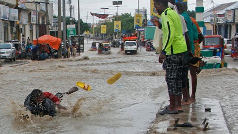 Ein Mann rutscht nach starken Regenfällen im Hochwasser aus. Nach starken Regenfällen und Sturzfluten sind am Horn von Afrika über 300 Menschen getötet worden. Millionen Menschen mussten flüchten. (Foto: dpa Bildfunk, picture alliance/dpa/AP | Farah Abdi Warsameh)