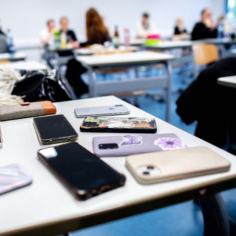 picture alliancedpa | Hauke-Christian Dittrich (Foto: dpa Bildfunk, Handys liegen im Klassenzimmer auf dem Tisch: Neuseeland will Handys an Schulen verbieten)