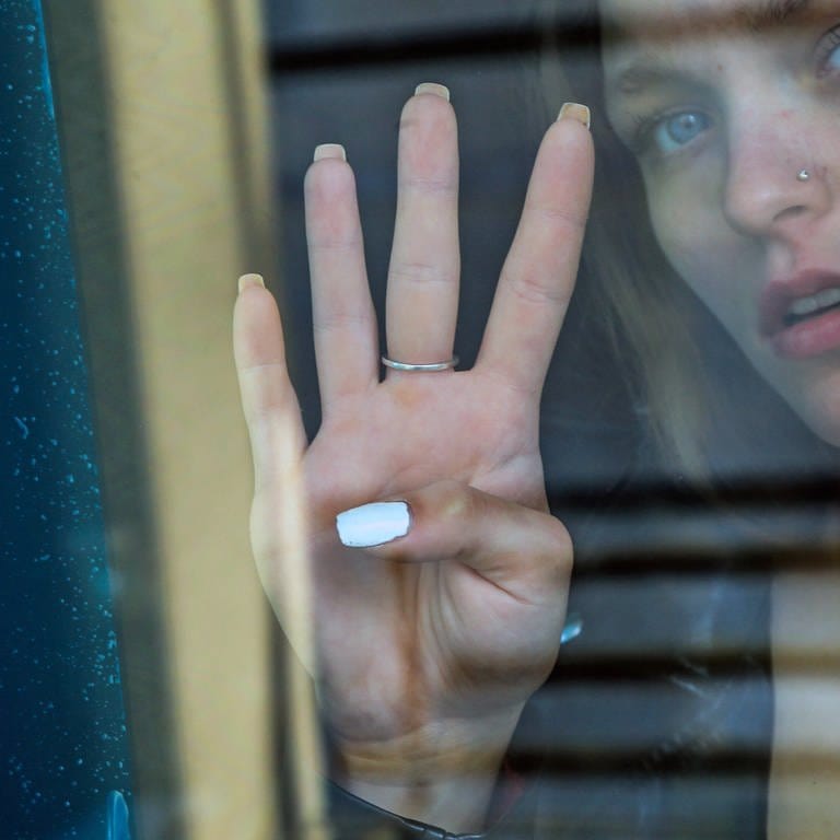 Frau am Fenster macht mit der Hand das internationale Hilfezeichen in Situationen mit Gewalt (Foto: IMAGO, IMAGO / Rolf Kremming (Symbolbild))