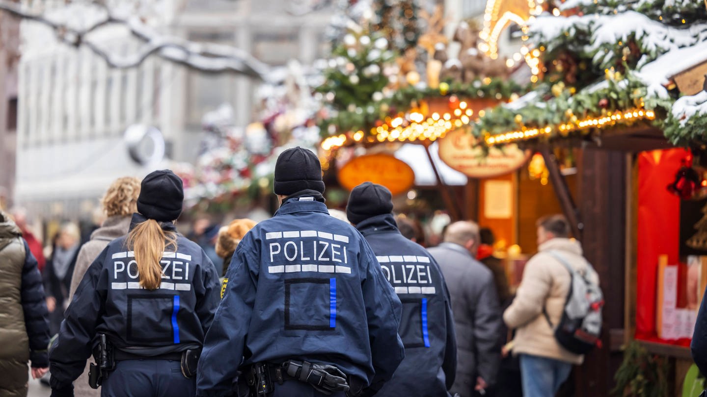 Polizisten von hinten auf dem Weihnachtsmarkt in Stuttgart: Polizei will ihre Präsenz erhöhen nach dem Anschlagspläne bekannt wurden. (Foto: IMAGO, IMAGO / Arnulf Hettrich)