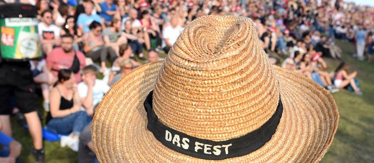 Ein Besucher des Open-Air-Festivals «Das Fest» in der Günther-Klotz-Anlage trägt einen Strohhut mit dem Namen der Veranstaltung. Bis einschließlich 21. Juli 2019 treten auf mehreren Bühnen zahlreiche Musiker auf. (Foto: dpa Bildfunk, picture alliance/dpa | Uli Deck)