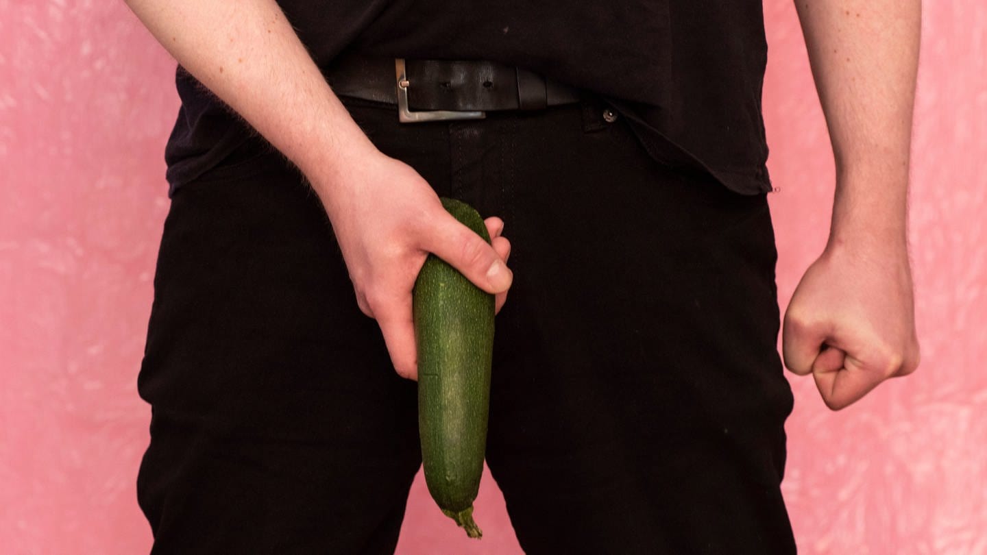 Ein Mann hält eine Zucchini als Penis an seine Hose. Bei einer Studie wurde festgestellt, dass es einen Zusammenhang zwischen Weihnachten und Penisbrüchen gibt. (Foto: IMAGO, IMAGO / Pond5 Images)