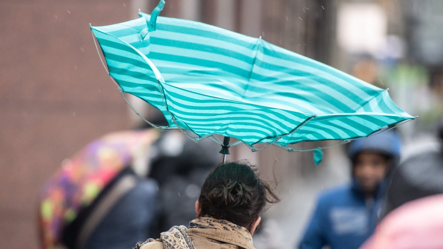 Eine Sturmböe erfasst in der Innenstadt von Frankfurt den Regenschirm einer Frau. (Foto: dpa Bildfunk, picture alliance/dpa | Boris Roessler)