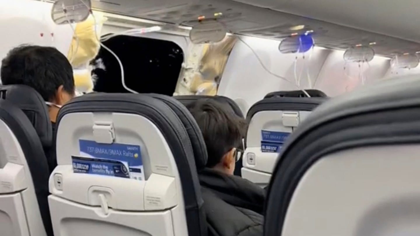 Dieses Bild aus einem von Elizabeth Le zur Verfügung gestellten Video zeigt Passagiere, die in einer Boeing 737-9 Max in der Nähe des abgerissenen Kabinenteils samt Fenster sitzen. (Foto: dpa Bildfunk, picture alliance/dpa/Elizabeth Le | Elizabeth Le)