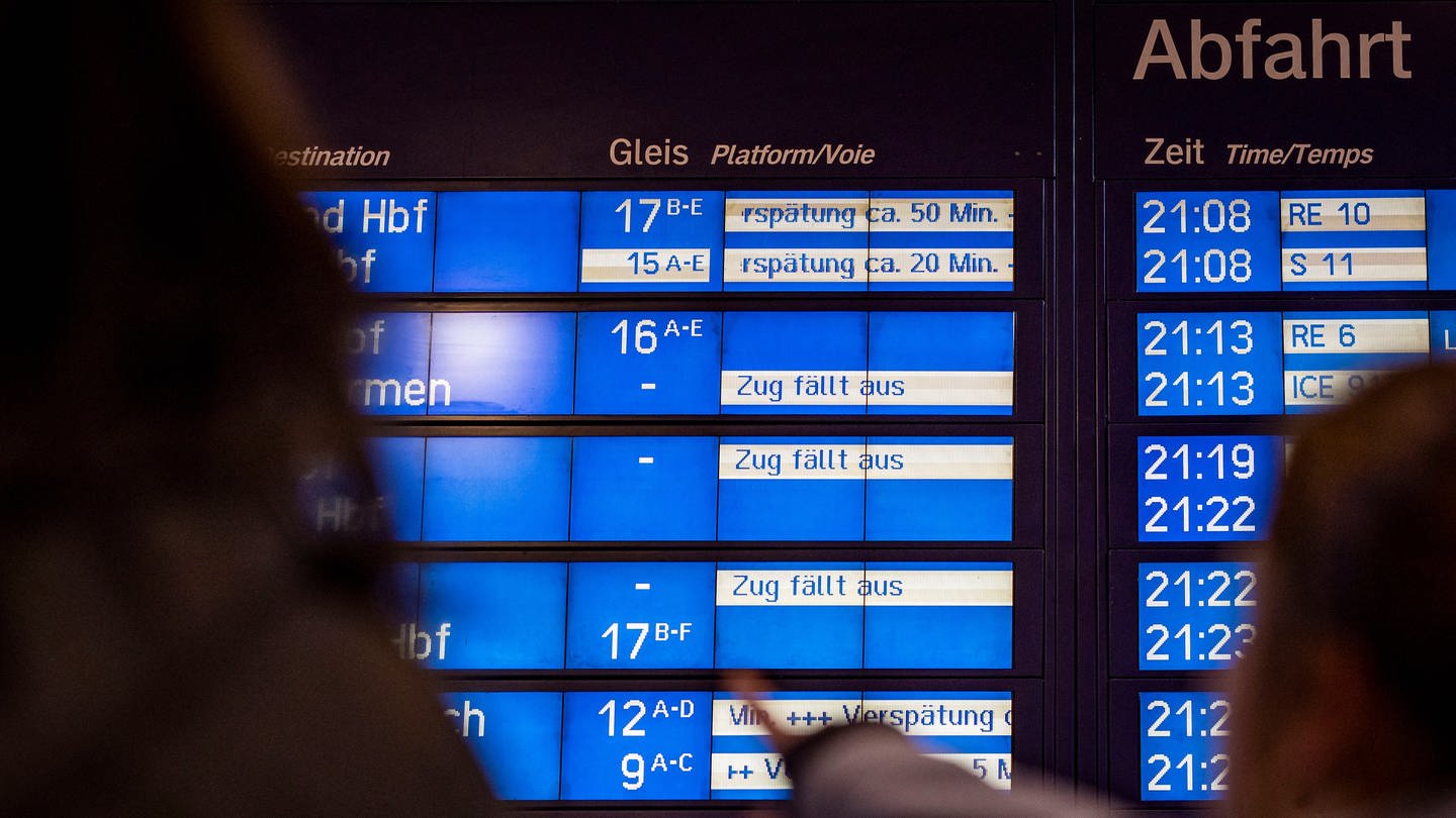 Reisende schauen auf die Anzeigetafel, eine Frau zeigt mit dem Finger auf den Schriftzug Zug fällt aus. (Foto: dpa Bildfunk, picture alliance/dpa | Christoph Reichwein)