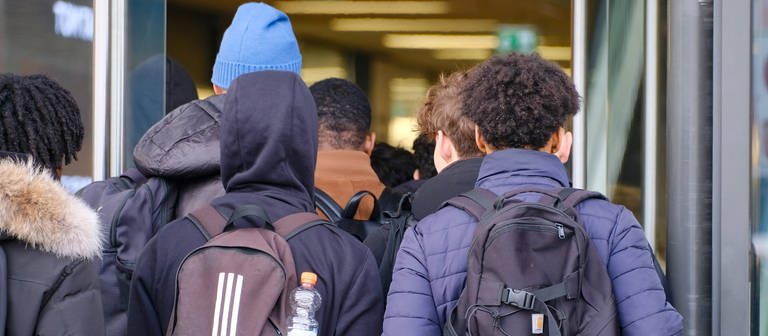 Jugendliche gehen nebeneinander gereiht in das Schulgebäude. Steigt die Gewalt an deutschen Schulen? (Foto: IMAGO, Funke Foto Services)