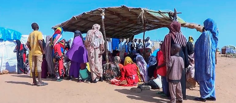 Sudanesische Geflüchtete versammeln sich vor einem Feldlazarett. Seit Mitte April kämpfen im Sudan die Streitkräfte unter der Führung des amtierenden Staatschefs Abdel Fattah al-Burhan gegen die paramilitärischen RSF. Nach UN-Angaben sind mehr als sieben Millionen Menschen im Land auf der Flucht.  (Foto: dpa Bildfunk, picture alliance/dpa/AP | Uncredited)