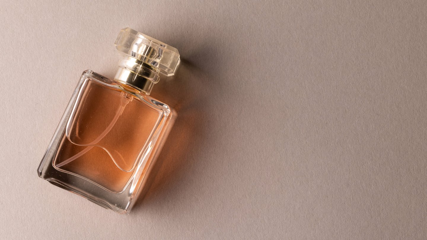 Eine Flasche Parfum vor hellbraunem Hintergrund (Symbolbild) (Foto: IMAGO, IMAGO / VectorFusionArt)