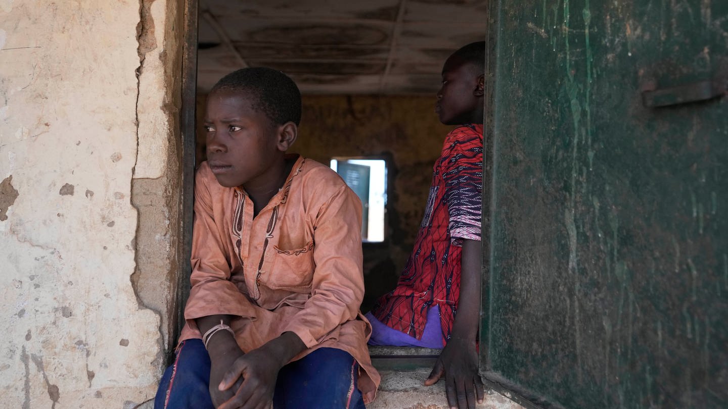 Ein Kind sitzt an einem Fenster eines Klassenzimmers in der LEA Primary and Secondary School Kuriga. Bei Angriffen an Schulen von bewaffneten Gruppen sind hunderte Schulkinder verschleppt worden. (Foto: dpa Bildfunk, picture alliance/dpa/AP | Sunday Alamba)