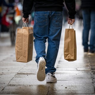 Ein Mann trägt Einkaufstauschen -- Laut einer Studie zahlst du oft zu viel. Spielekonsolen, Autos und Co. sind nämlich in bestimmten Monaten günstiger. (Foto: dpa Bildfunk, picture alliance/dpa/dpa-Zentralbild | Monika Skolimowska)
