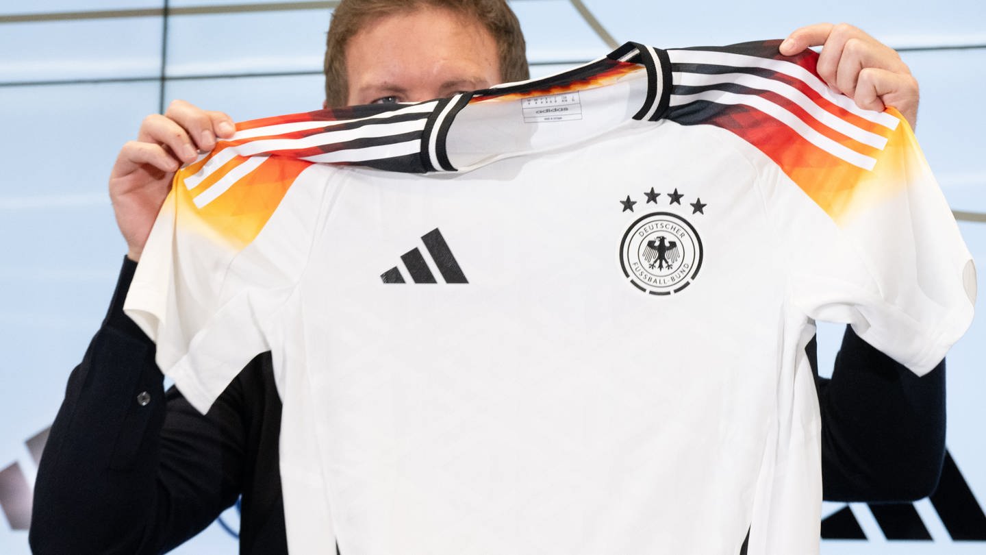 Bundestrainer Julian Nagelsmann hält auf einer Pressekonferenz das neue offizielle EM-Trikot des DFB-Teams hoch. (Foto: dpa Bildfunk, picture alliance/dpa | Boris Roessler)
