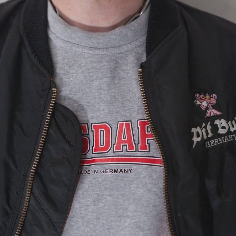 Ein Consdaple-Shirt unter einer geöffneten Bomberjacke. In Neonazikreisen wird diese Kombination gewählt, um die Buchstaben NSDAP aus der Jacke herausblitzen zu lassen. (Foto: IMAGO, IMAGO / Rüdiger Wölk)