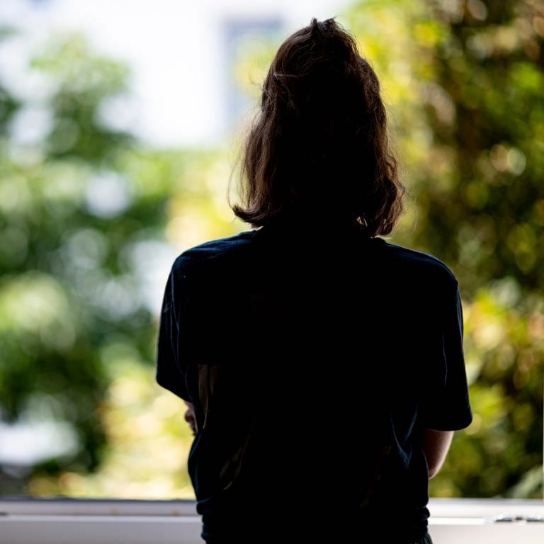 Eine Frau steht in ihrer Wohnung an einem Fenster. (Foto: dpa Bildfunk, picture alliance/dpa | Fabian Sommer)
