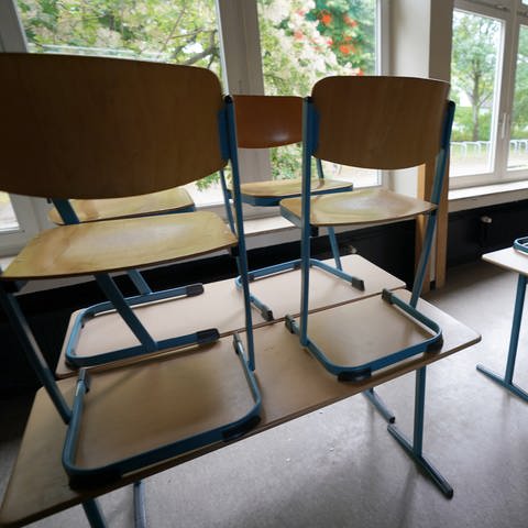Stühle stehen in einem Klassenraum in einer Schule auf den Tischen.