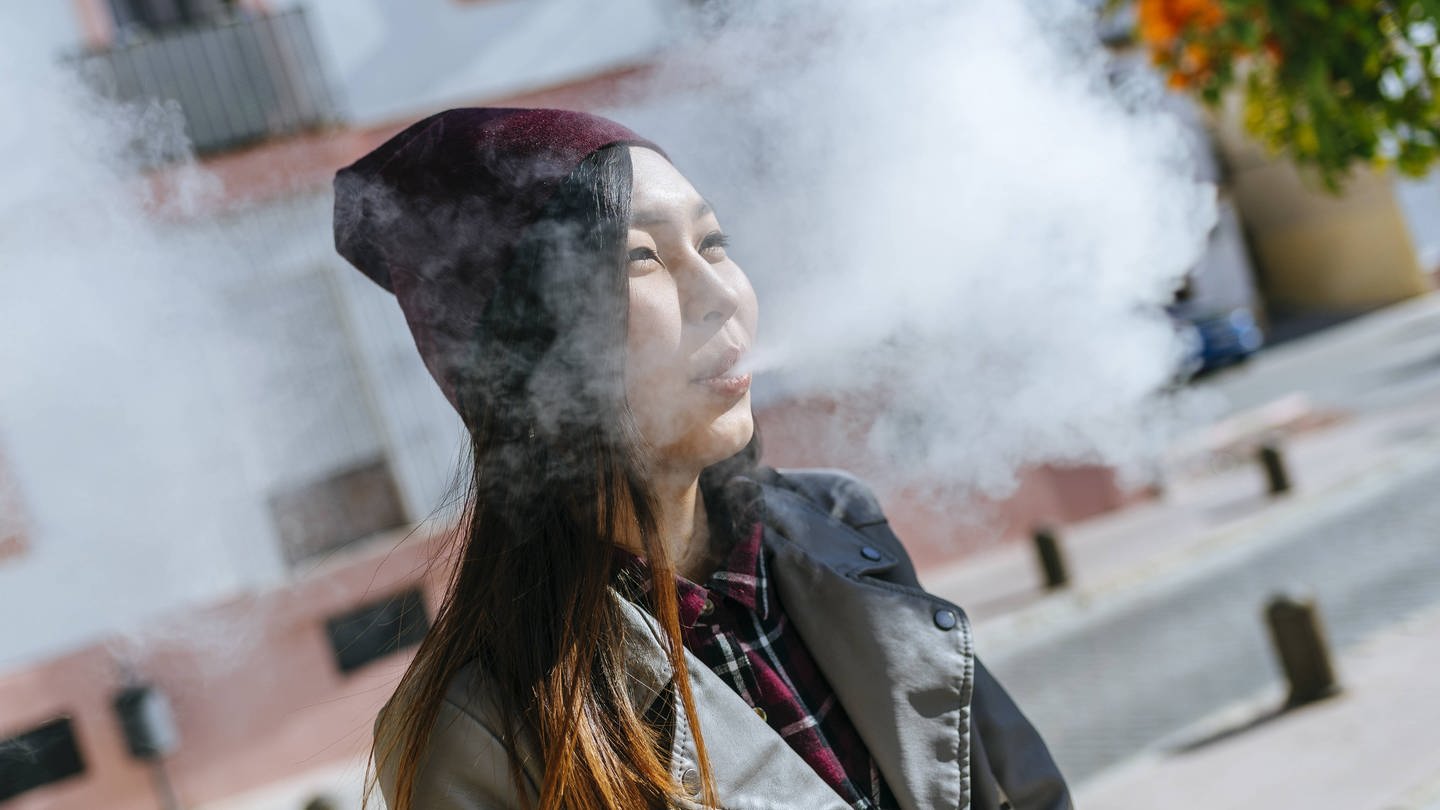 Young woman blowing out smoke from electronic cigarette model released Symbolfoto (Foto: IMAGO, IMAGO / Westend61)
