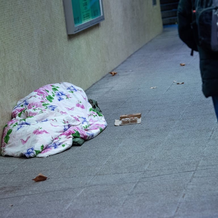 Ein Mann geht an einem schlafenden Mann vorbei, der in einer Unterführung liegt. (Foto: dpa Bildfunk, picture alliance/dpa | Sebastian Gollnow)
