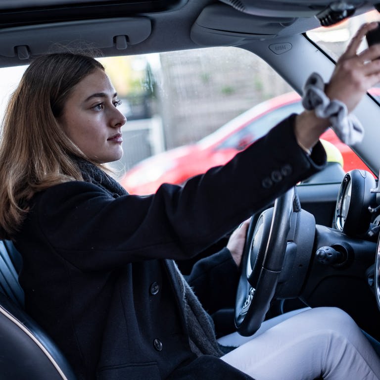 Eine junge Autofahrerin stellt den Rückspiegel ein. Viele junge Menschen machen ihren Führerschein mit 17 Jahren - um anshcließend begleitend zu fahren. Der Führerschein mit 16 Jahren war im Gespräch - er kommt aber nicht, weil die EU über die Regeln bestimmt. (Foto: IMAGO, IMAGO / Felix Jason)