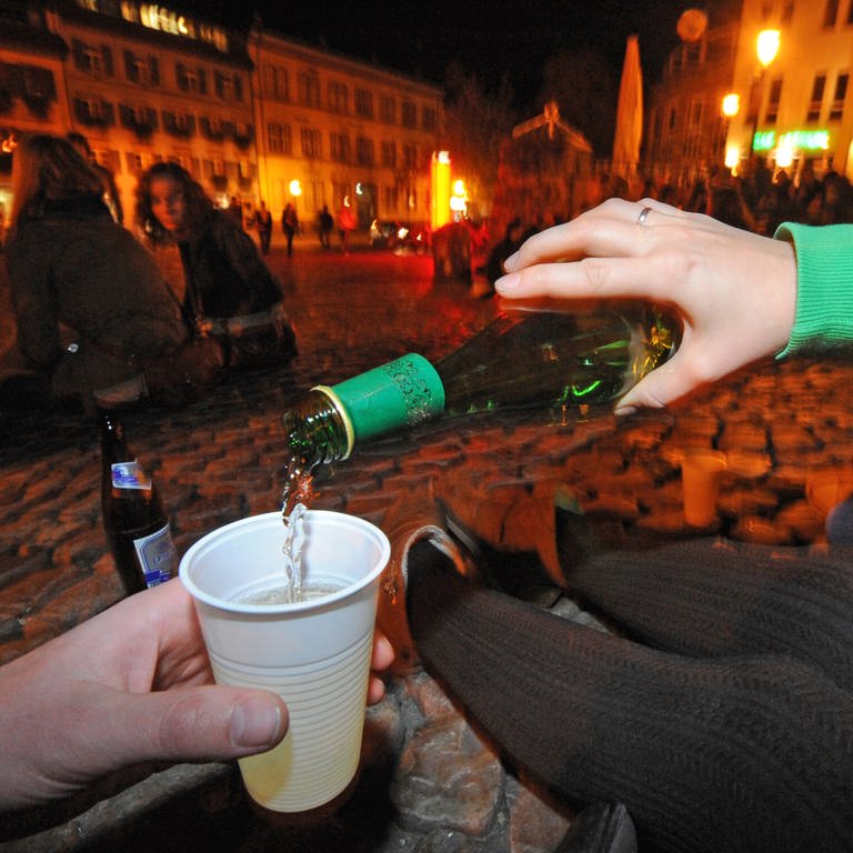  Jugendliche sitzen auf dem Augustinerplatz in der Innenstadt von Freiburg (Baden-Württemberg) und trinken Alkohol. 