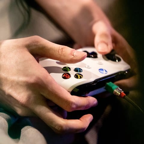 Die Hände eines Spielers sind an einem Xbox Controller zu sehen. 