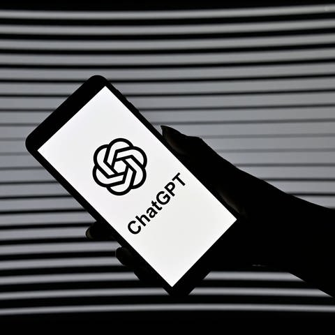 Smartphone in einer Hand mit dem ChatGPT Logo