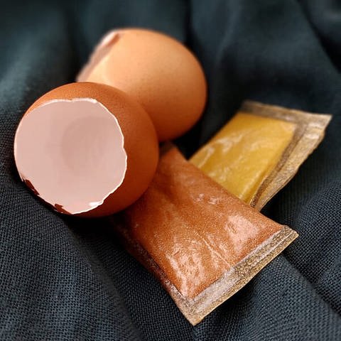 Eine Eierschale liegt neben einer nachhaltigen Verpackung (Foto: EDGGY / Cora Schmetzer)