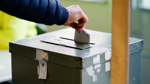 Person wirft Wahlzette in Wahlurne