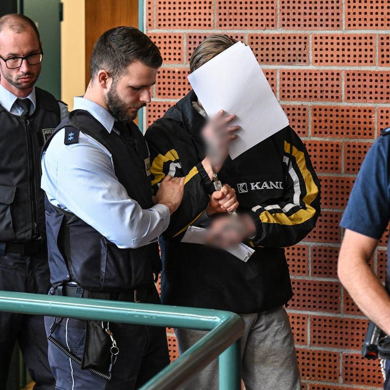 Ein wegen Mordes Angeklagter betritt den Gerichtssaal und verdeckt mit mehreren Blättern Papier sein Gesicht. (Foto: dpa Bildfunk, picture alliance/dpa | Felix Kästle)