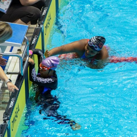 Die Schwimmerin Sara Ghandoura aus Saudi Arabien hat gedacht, dass sie schon im Ziel ist. Sie war aber erst auf der Hälfte der Strecke. Ihre Konkurrentin Esmeralda Encarnacion Despiau aus Puerto Rico hat das bemerkt und begleitet sie für den Rest der Strecke. (Foto: IMAGO, IMAGO / GEPA pictures)