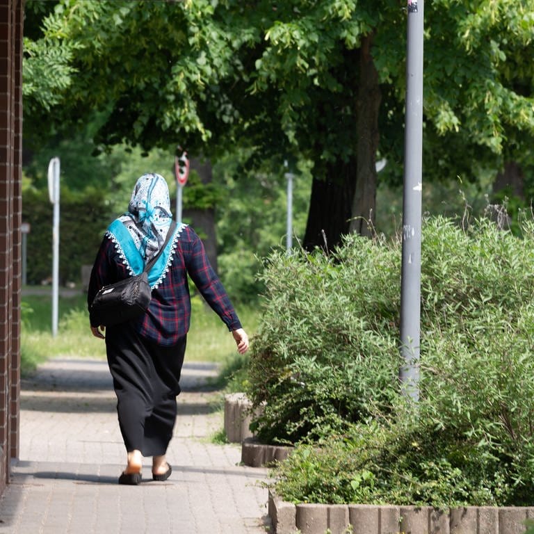 Muslimische Frau mit Kopftuch läuft an einem AfD-Wahlplakat vorbei. (Foto: dpa Bildfunk, picture alliance/dpa/dpa-Zentralbild | Sebastian Kahnert)