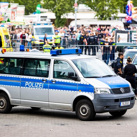 Polizisten und ein Polizeifahrzeug stehen auf dem Schützenplatz. Bei einem Unfall mit einem Auto bei einer Autoshow auf dem Schützenplatz in Hannover sind mehrere Menschen verletzt worden.