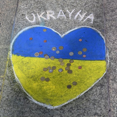 Mit einem Herz in den Farben der Ukraine auf dem Gehweg werden Spenden gesammelt.