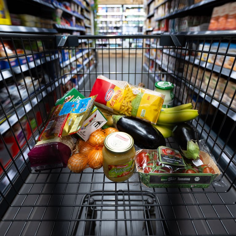 Verschiedene Lebensmittel liegen in einem Supermarkt in einem Einkaufswagen. Immer mehr Deutsche müssen sich beim Essen einschränken.