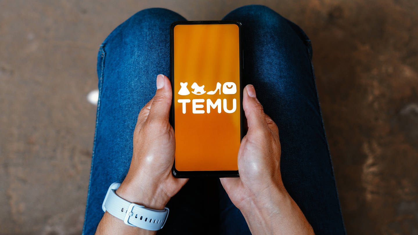 Jemand hält ein Handy mit dem Logo von Temu in der Hand. (Foto: IMAGO, Zoonar)