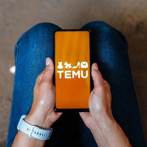 Jemand hält ein Handy mit dem Logo von Temu in der Hand.