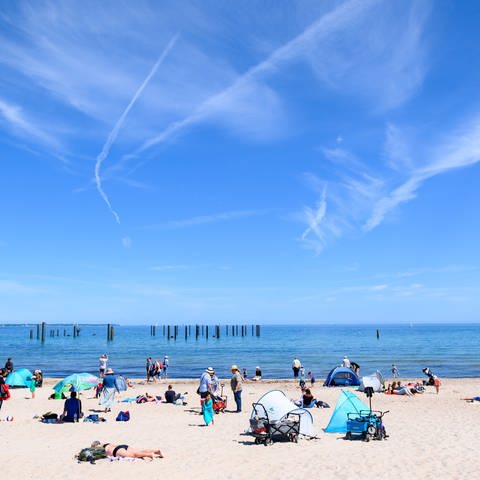 Menschen genießen das Wetter und ihren Urlaub am Strand an der Ostsee.