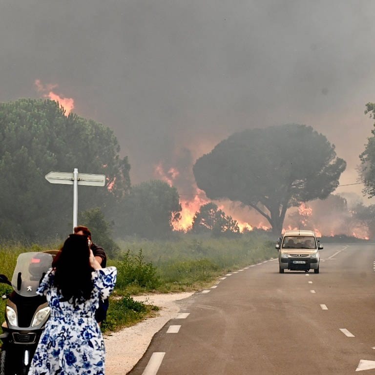 Eine Frau fotografiert in Saint-Andre in der Nähe von Argeles-sur-Mer im Südwesten Frankreichs einen Großbrand, der zur Evakuierung von rund 3000 Touristen von nahegelegenen Campingplätzen geführt hat. (Foto: dpa Bildfunk, picture alliance/dpa/AFP | Raymond Roig)