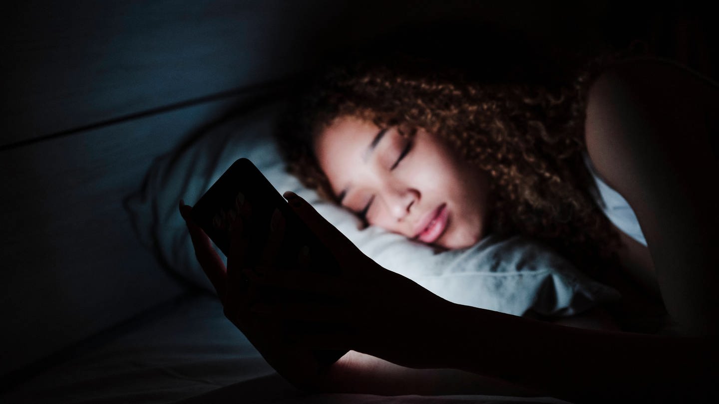 Handy im Bett: Die App Pokémon Sleep soll beim Durchschlafen helfen. (Foto: IMAGO, IMAGO / Westend61)