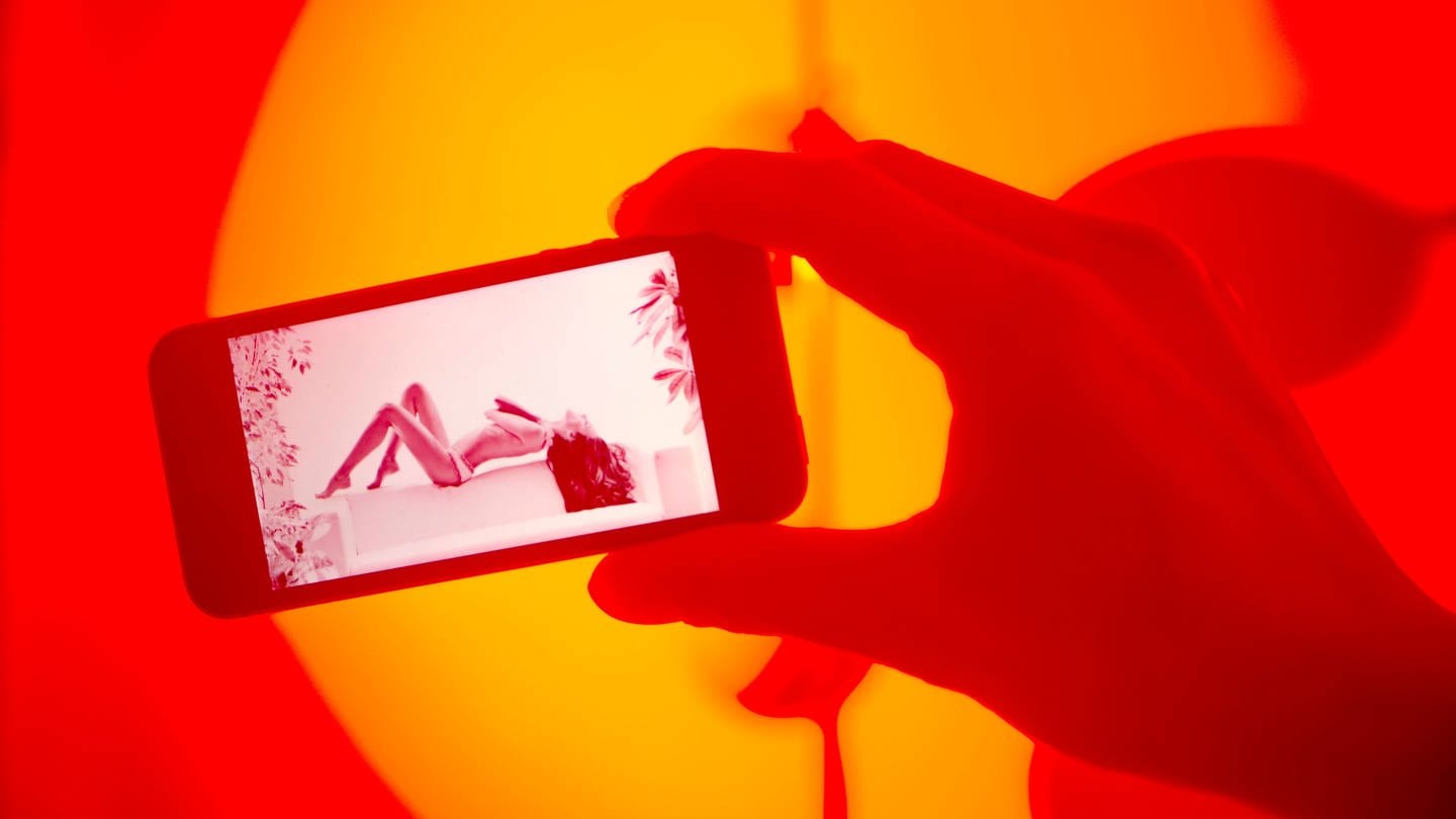 Eine Person guckt sich pornografisches Material auf einem Smartphone an. (Foto: IMAGO, Elmar Gubisch)