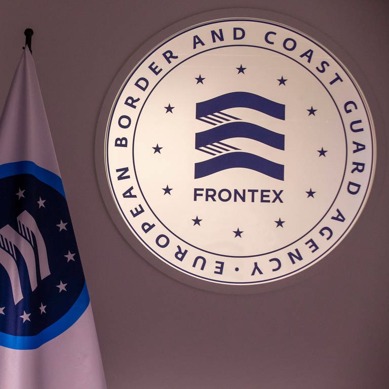 Logo der EU-Grenzschutzagentur Frontex neben Fahne von Frontex und EU