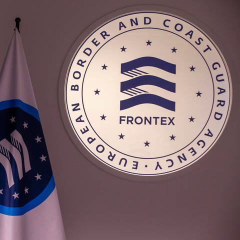 Logo der EU-Grenzschutzagentur Frontex neben Fahne von Frontex und EU (Foto: IMAGO, IMAGO/Belga)