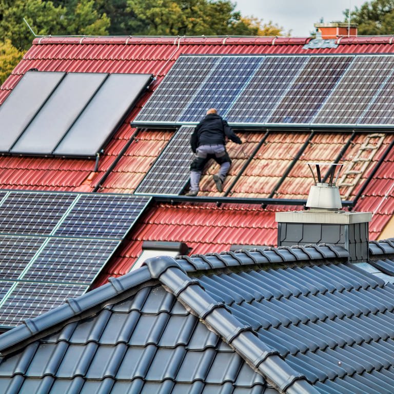 Ein Mann montiert eine Solaranlage auf einem Dach