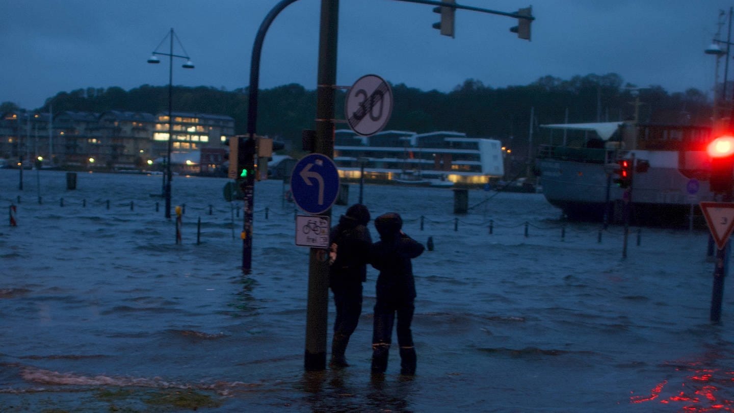 Zwei Spaziergänger betrachten das Hochwasser in Flensburg. (Foto: IMAGO, IMAGO / Willi Schewski)