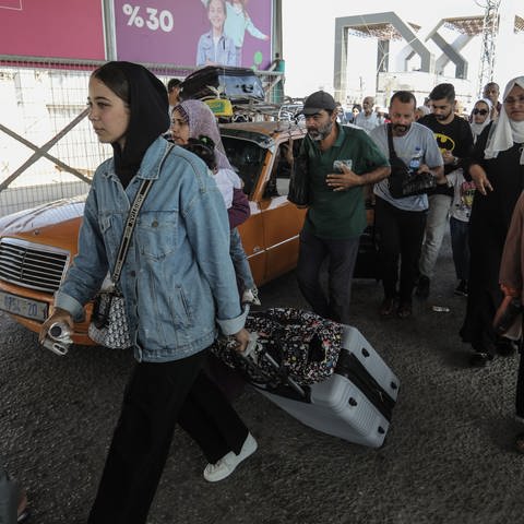 Palästinenser tragen Gepäck am Grenzübergang zwischen dem Gazastreifen und Ägypten. Verletzte Palästinenser und Inhaber ausländischer Pässe können über den Grenzübergang Rafah evakuiert werden.