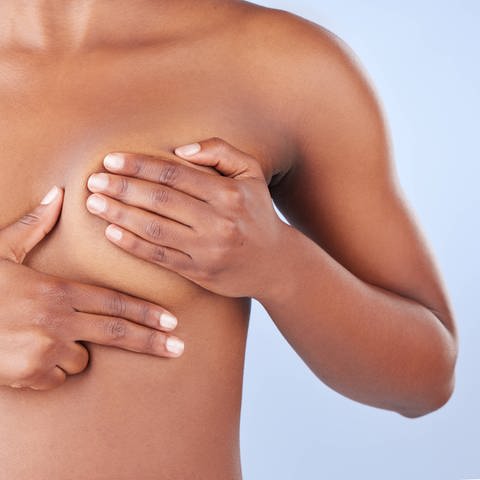 Eine Frau tastet ihre Brust nach Knoten ab. Etwa 290 000 Frauen in Großbritannien könnten künftig vorbeugend ein Medikament gegen Brustkrebs nehmen.