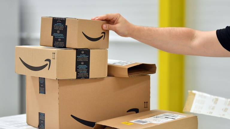 Im "Shopfloor" des Amazon Verteilzentrums für Pakete und Päckchen stehen Paket-Sendungen auf einem Tisch. Die EU-Komission hat ein Prüfverfahren gegen Amazon eingeleitet (Symbolbild) (Foto: dpa Bildfunk, picture alliance/dpa/dpa-Zentralbild | Martin Schutt)