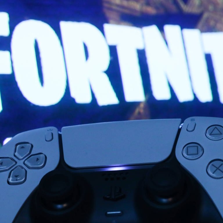 Auf einem Bildschirm ist das Fortnite-Logo zu sehen, davor ein Controller für die PlayStation 5.